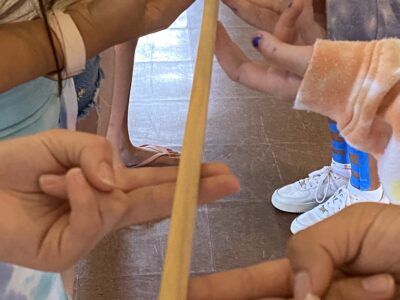 Teens' hands lifting a piece of wood together