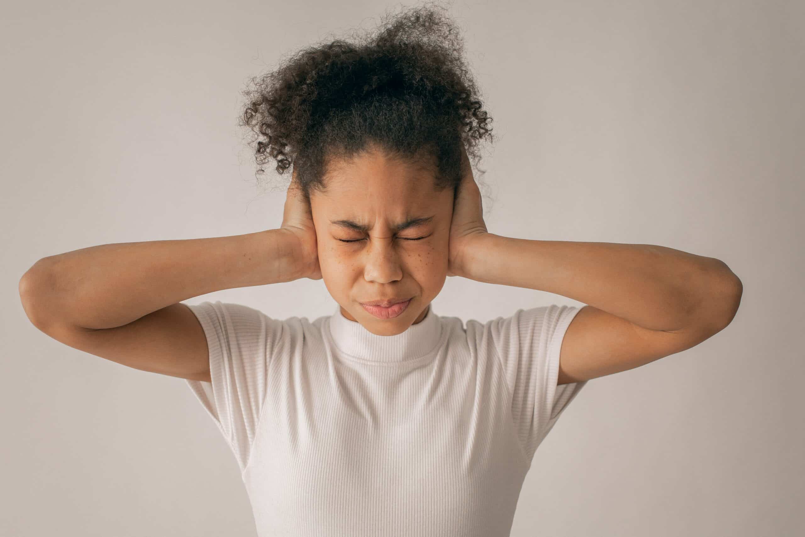 Girl with eyes closed and hands over her ears