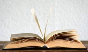 Open book on wooden table with two pages flapping up in the air