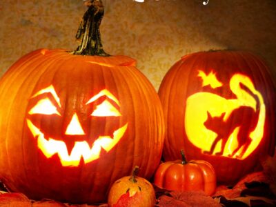 Two carved jack-o-lanterns, one with a smiling face, one with a cat arching its back.