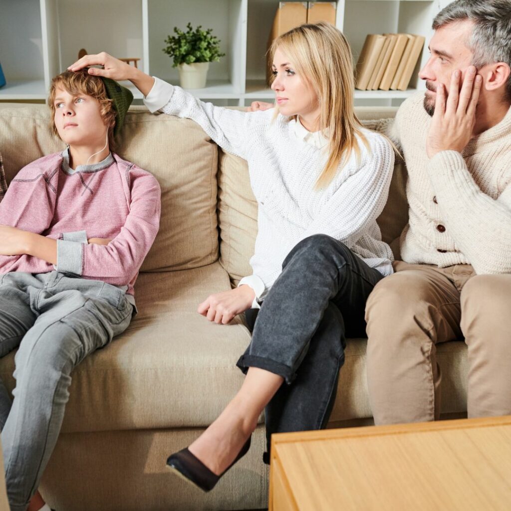 Mother and father on couch with distressed looking teenage son.