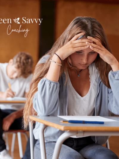 Teenage girl looking down at school work with concern in a classroom full of other students working.